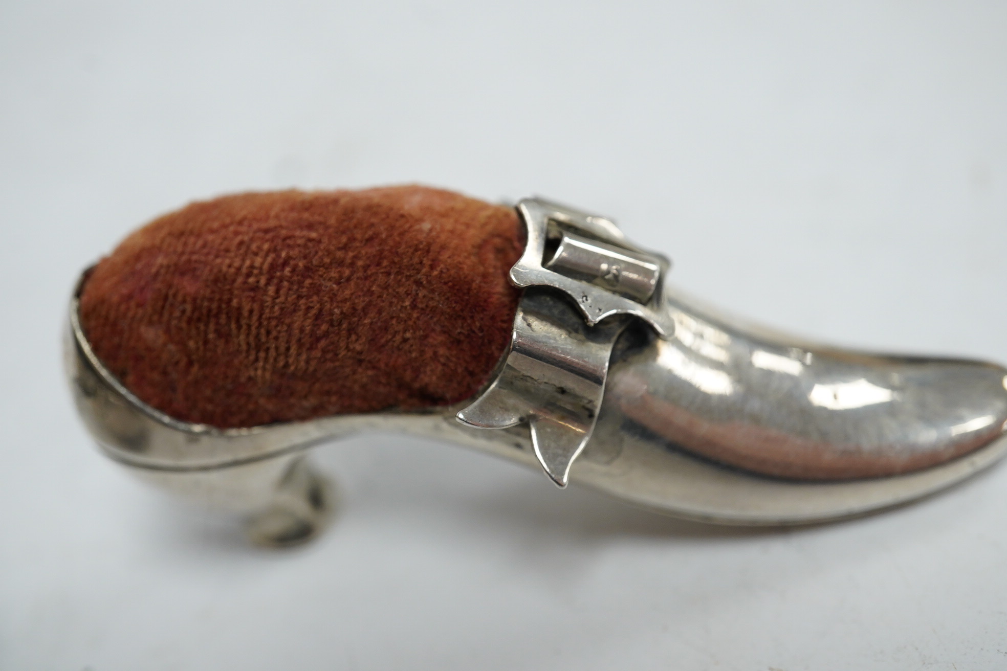 An Edwardian novelty silver pin cushion, modelled as a hatching chick, by Sampson Mordan & Co, Sheffield, 1906, height 43mm (hole), together with a late Victorian shoe pin cushion, by Adie & Lovekin, Birmingham, 1892, Co